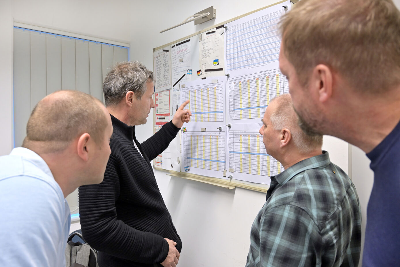 Das Team der Störmeldezentrale: mehrere männlich gelesene Personen schauen auf ein Whiteboard.