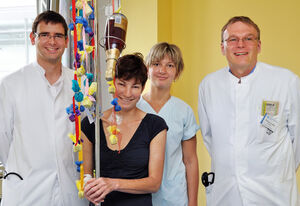 Mit Pralinen und einer Sektflasche an ihrem Infusionsständer bedankte sich die gestern aus dem UKJ entlassene HUS-Patientin Anke J. bei Oberarzt Martin Busch, Schwester Claudia und Prof. Gunter Wolf. Foto: Szabo/UKJ