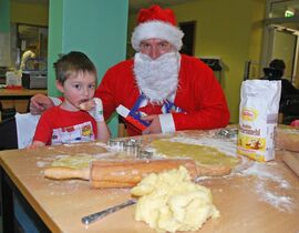 Der kleine Ole freut sich, dass der Nikolaus beim Plätzchenbacken hilft. Foto: Schleenvoigt / UKJ