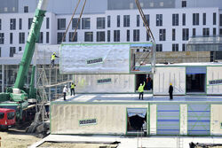 Ein 200-Tonnen-Kran montiert zurzeit 63 Raumzellen vor dem jetzigen Haupteingang des Universitätsklinikums Jena. Aus den von der Cadolto Thüringen GmbH vorgefertigten Elementen entsteht ein neues Bettenhaus. Foto: UKG / Grau