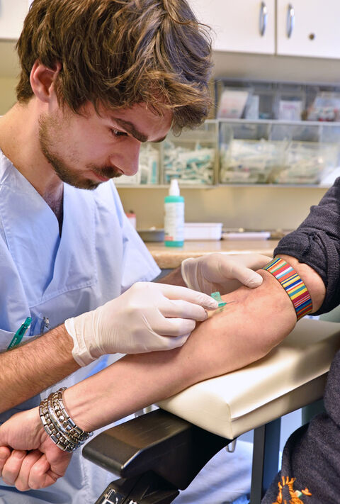 Martin Hocquel, Pflege-Azubi im 2. Lehrjahr, nimmt einem Patienten Blut ab. (Foto: UKJ/Szabó)