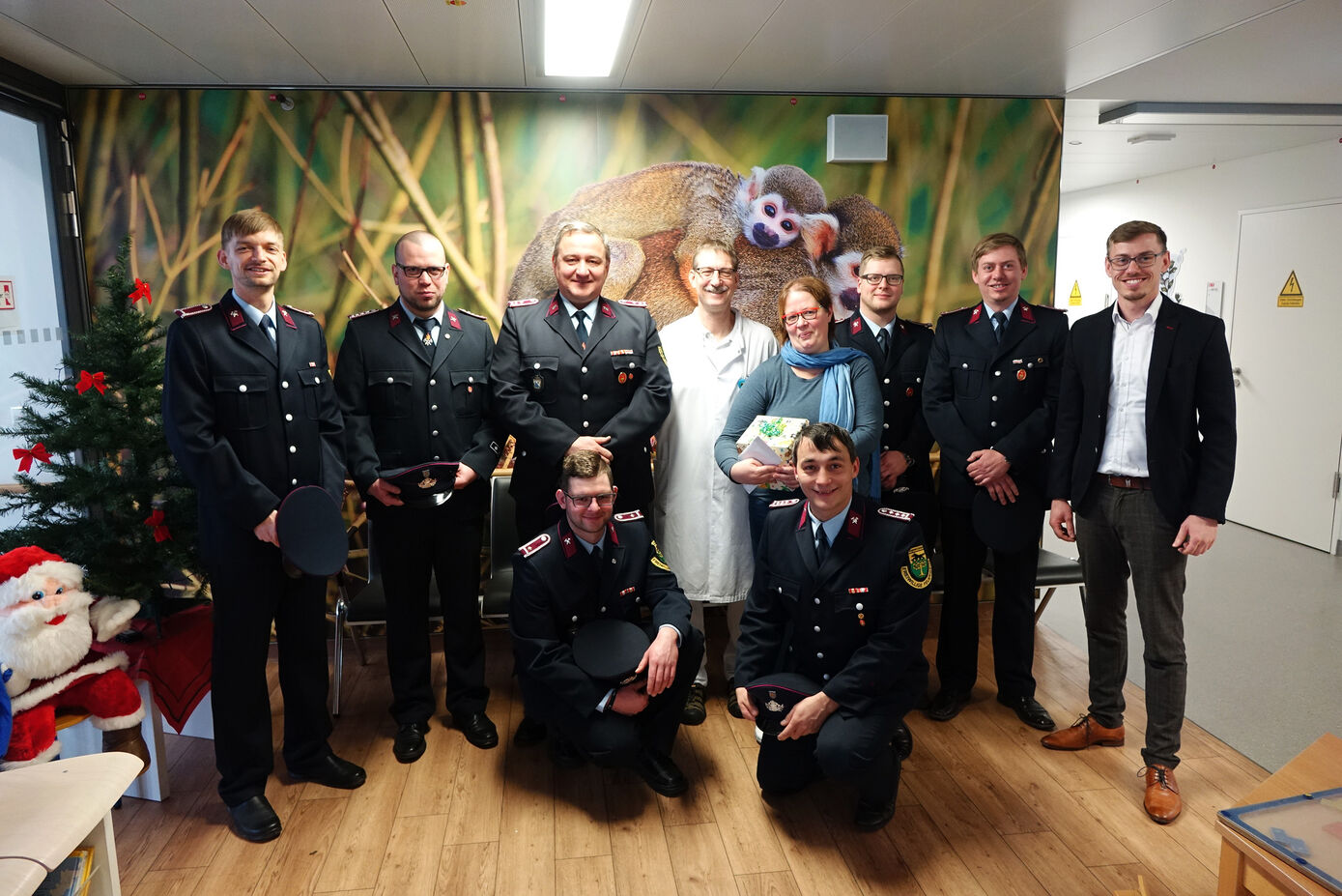 Alexander Wilhelm (vorne rechts) überreicht gemeinsam mit seinen Kameraden des Feuerwehrvereins Langenwolschendorf die Spende an Prof. Dr. Hans Proquitté (4.v.l.), stellvertretender Direktor der Klinik für Kinder- und Jugendmedizin am UKJ, und Kerstin Pechmann (4.v.r.), Pflegedienstleitung der Kindernotaufnahme am UKJ. Foto: UKJ