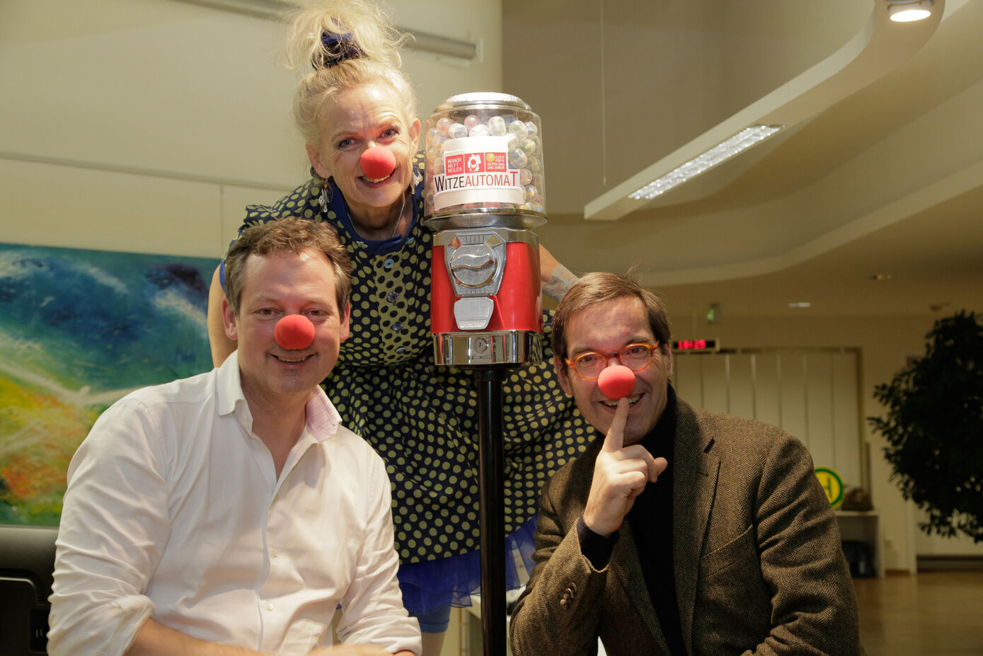 Ein weiterer humorvoller Baustein auf der Palliativstation am UKJ: Dr. Eckart von Hirschhausen übergibt Deutschlands ersten Witzeautomaten. PD Dr. Ulrich Wedding, Chefarzt der Palliativstation (rechts im Bild) und Klinik-Clown Frau Blau freuen sich. Foto: UKJ