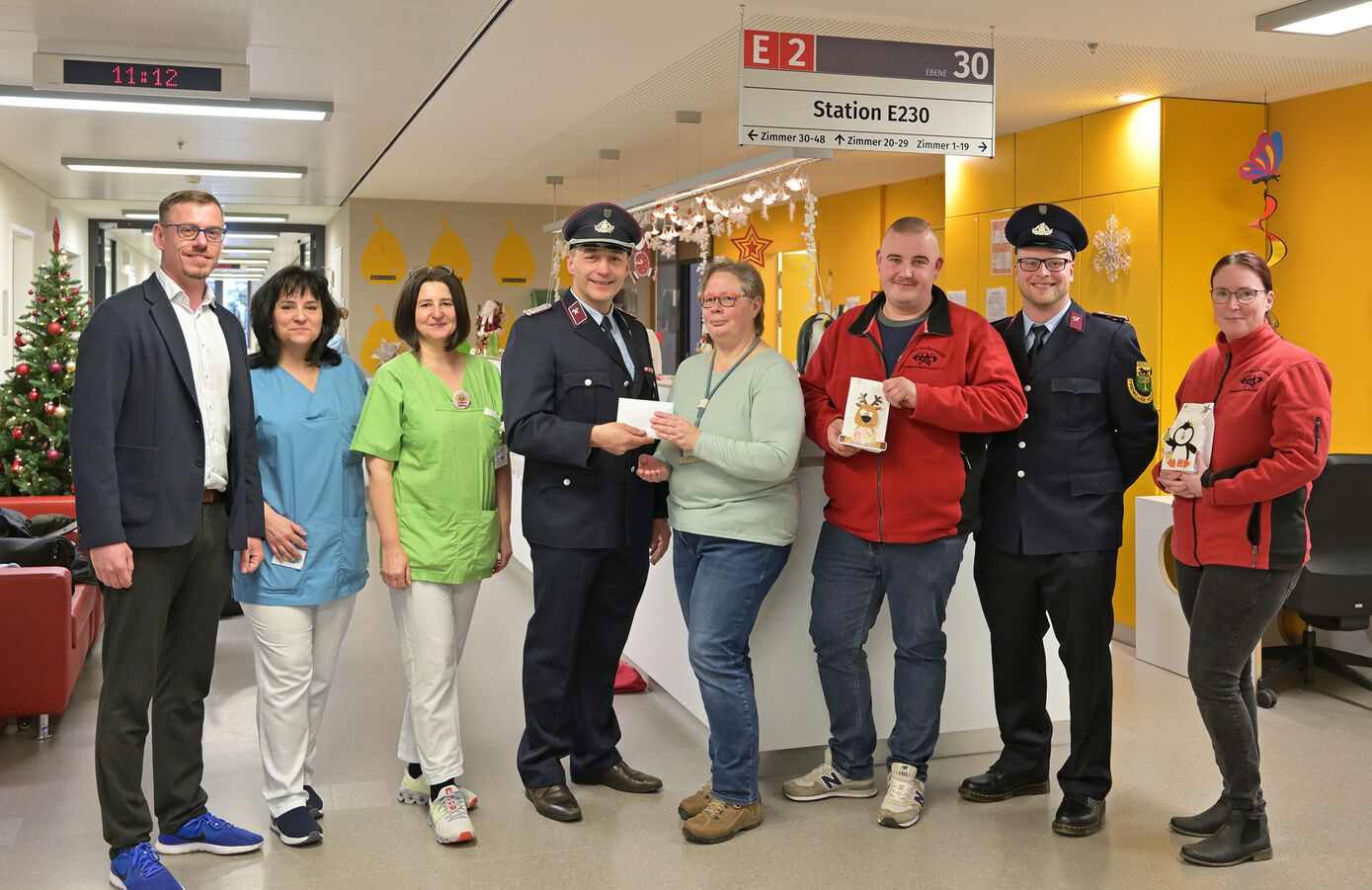 Feuerwehrmann Alexander Wilhelm (4.v.l.) übergibt die Spende an Kerstin Pechmann (4.v.r.), Pflegedienstleitung der Station E230. Foto: UKJ/Szabó 