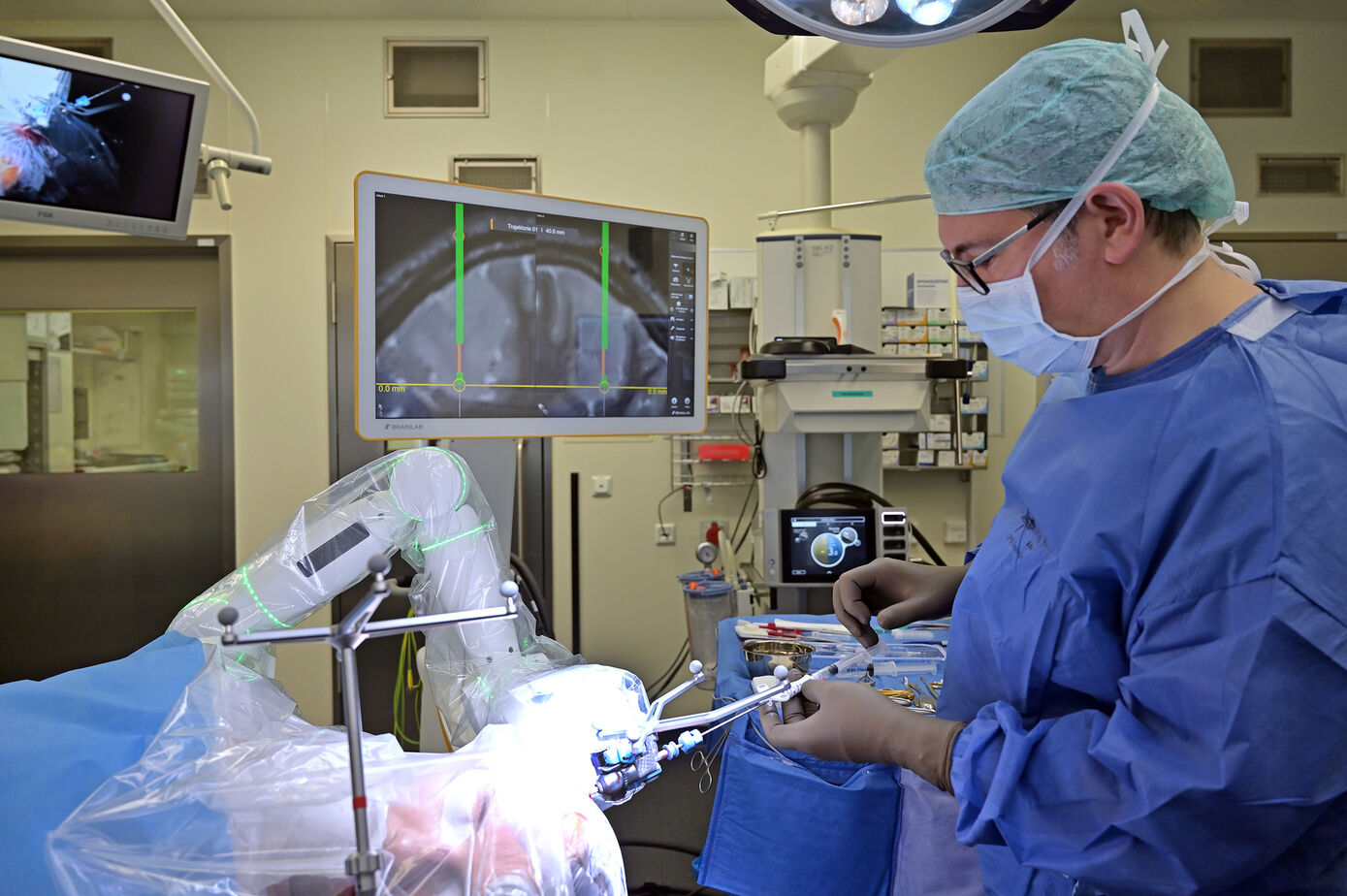 Der Roboterarm dient als präzise Führungshilfe für die Biopsienadel im Hirn. Die Position der Biopsienadel ist in Echtzeit im MRT-Bild erkennbar. Fotos: Szabó/UKJ