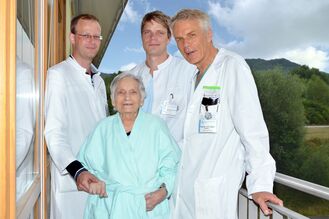 Prof. Dr. Rainer Figulla (Direktor Kardiologie, rechts), Oberarzt Dr. Alexander Lauten (Oberarzt Kardiologie, 2.v.r.) und Herzchirurgie-Oberarzt Dr. Tim Sandhaus (links) mit ihrer gemeinsamen Patientin kurz nach dem Einsatz der neuen Herzklappe am Universitätsklinikum Jena. Foto: UKJ