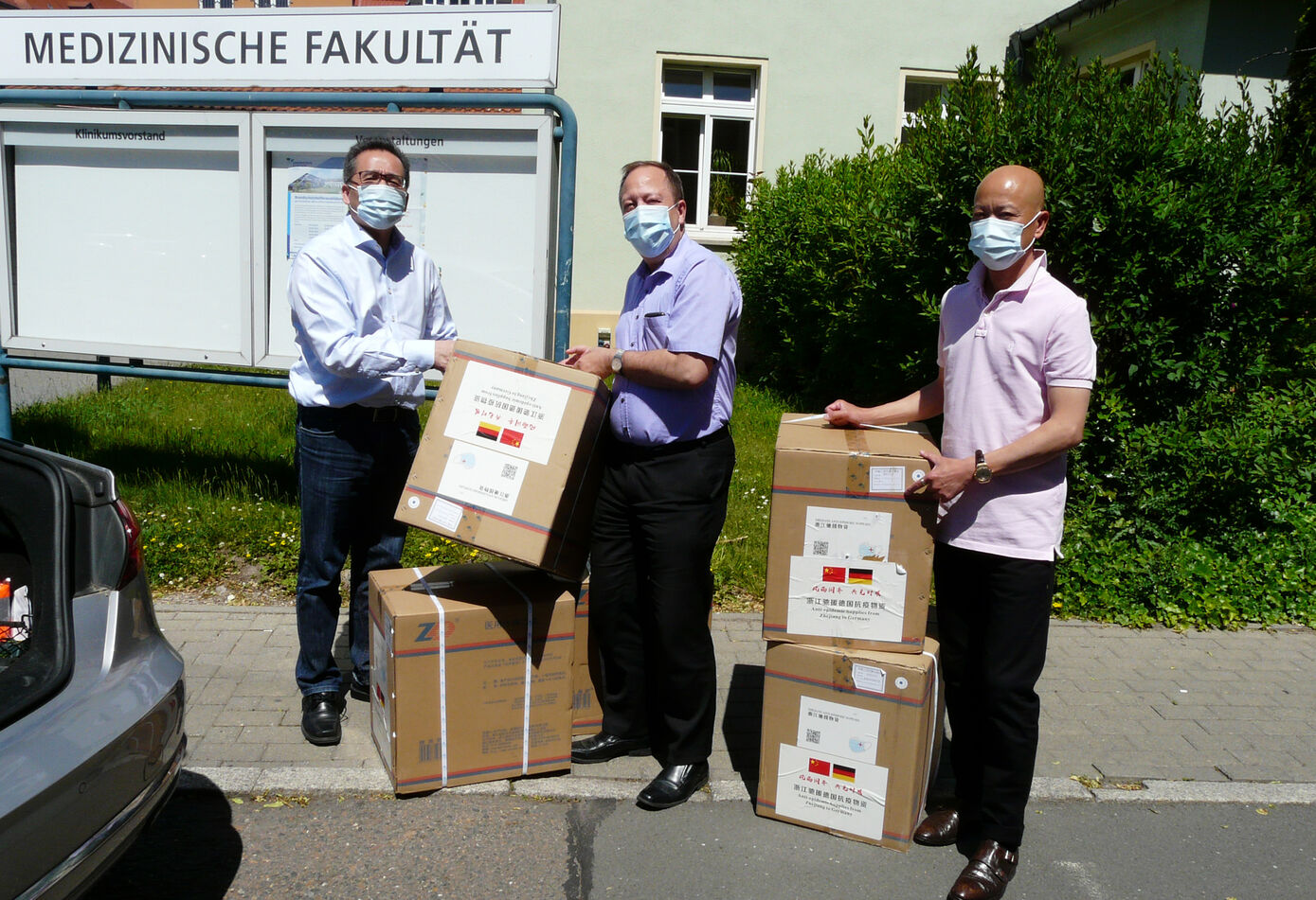 Lipo Hu (l.) und Zengya Ye (r.) vom Verein Kommission für Epidemieprävention der Überseechinesen in Deutschland übergaben 10.000 Schutzmasken an den Forschungskoordinator der Medizinischen Fakultät, Dr. Tobias Neumann (M.). Foto: Uta von der Gönna/UKJ