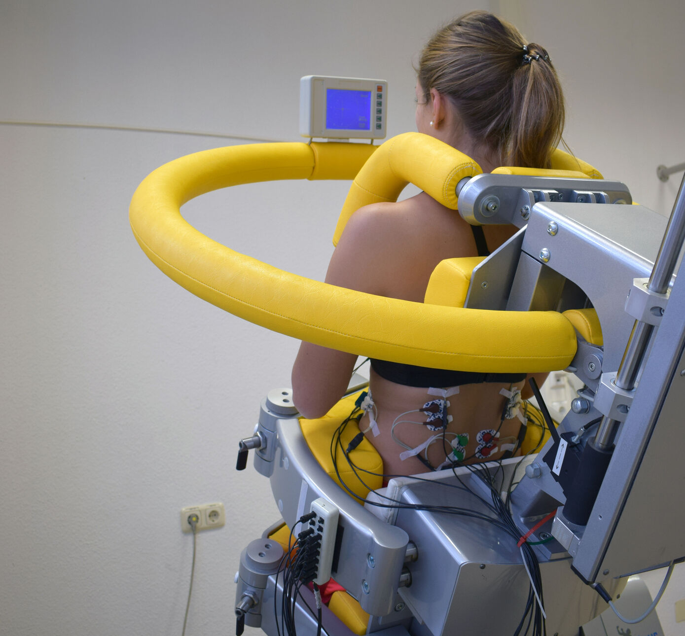 Bei den schmerzfreien Messungen werden kleine Oberflächenelektroden auf die Haut geklebt, um die Muskelaktivität zu bestimmen. In einem speziellen Trainingsgerät wird der Oberkörper dabei auch in eine Kippposition gebracht. Foto: Motoriklabor