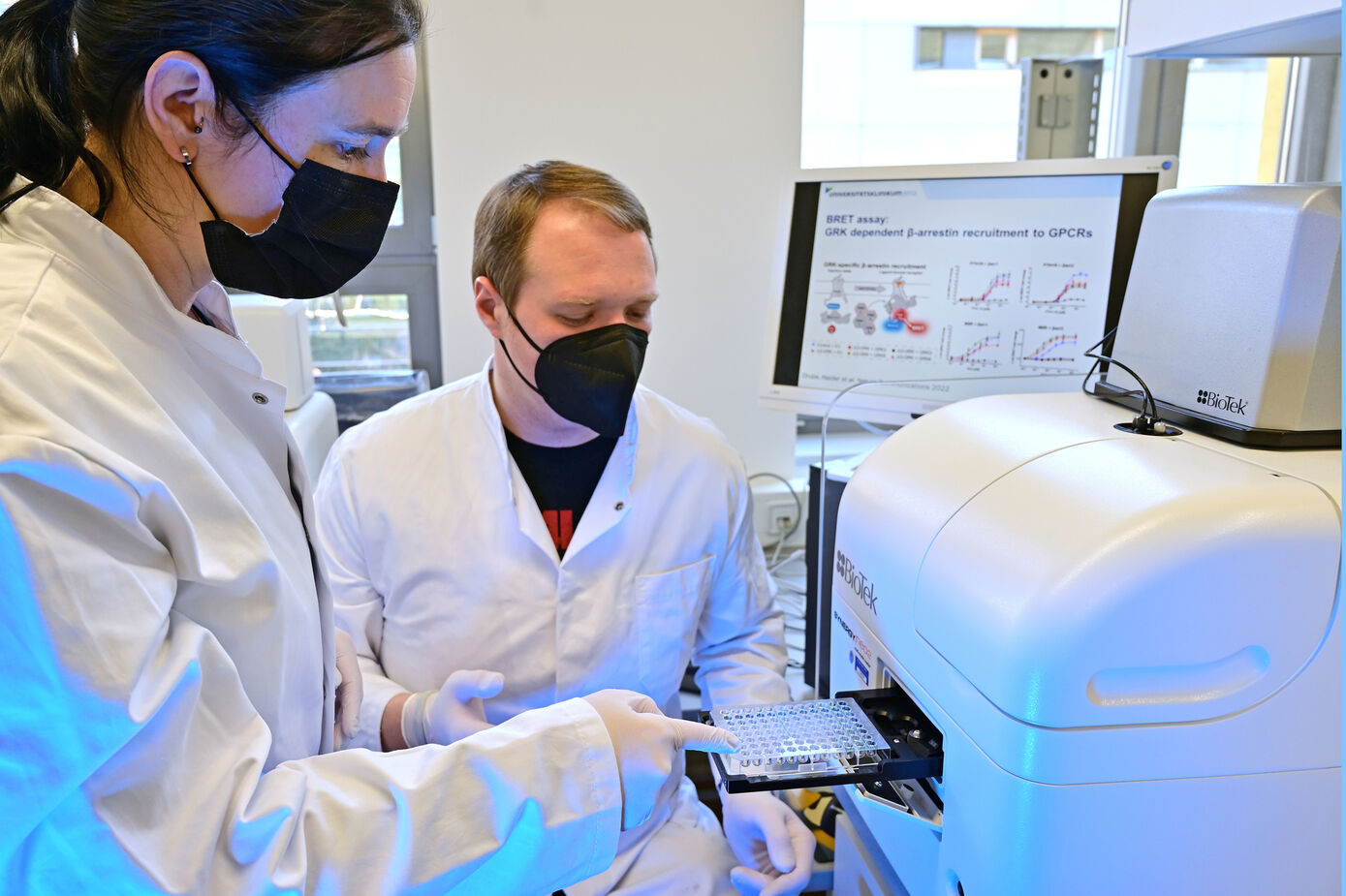 Dr. Julia Drube (l.) und Raphael Haider analysieren die Regulation G-Protein-gekoppelter Rezeptoren. Mit Hilfe ihres komplexen Zellsystems können sie dann bestimmen welche Enzyme dafür im Einzelfall notwendig sind. 
Foto: Michael Szabó/UKJ