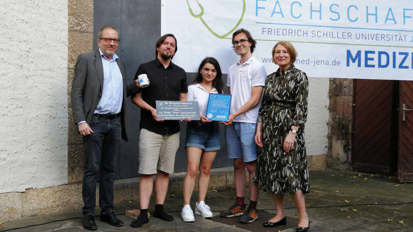 Zusammen mit UKJ-Vorstandssprecherin Dr. Brunhilde Seidel-Kwem (r.) für den UKJ-Förderverein und dem Dekan der Medizinischen Fakultät, Prof. Dr. Thomas Kamradt (l.) zeichnen Stefanie Völkel-Beltran (M.) und Sam Quaas (4.v.l.) von der Fachschaft PD Dr. Gregor Hayn-Leichsenring mit dem Janus-Cornarius-Lehrpreis 2022 aus. 
Foto: Uta von der Gönna/UKJ 
