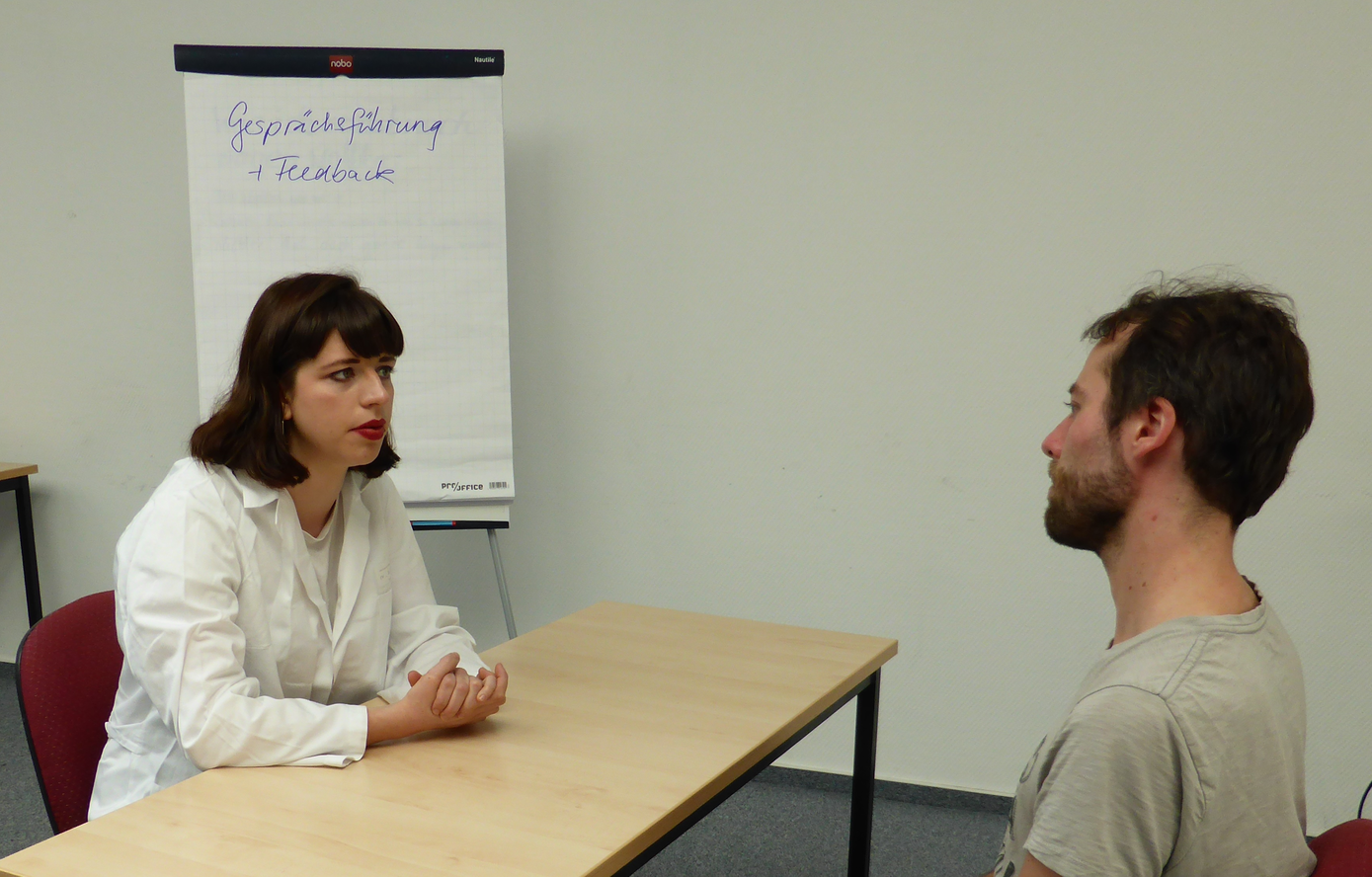 Ein Schauspielpatient (SP) übt mit einer Studentin in der Rolle der Ärztin ein Anamnesegespräch. Foto: Swetlana Philipp/Universitätsklinikum Jena